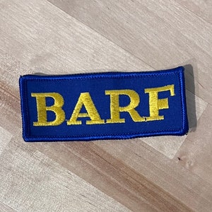 May include: A blue rectangular patch with the word "BARF" embroidered in gold thread.