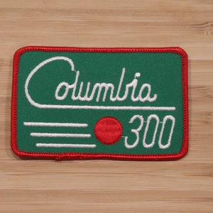 May include: Green and red embroidered patch with white text that reads "Columbia 300".