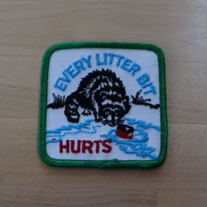 May include: Green and white embroidered patch with a raccoon and the text "Every Litter Bit Hurts".