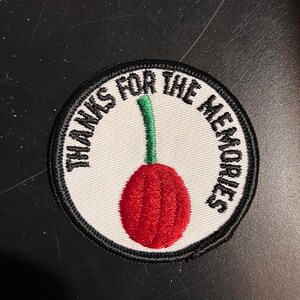 May include: A white round patch with black stitching and the text "Thanks for the memories" in a black circle around a red cherry with a green stem.
