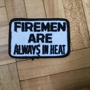 May include: White patch with black embroidered text that reads "Firemen Are Always In Heat".
