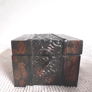 May include: A small wooden box with a carved design and a metal latch. The box is painted in shades of green and brown.