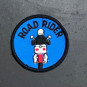 May include: A blue and black embroidered patch with the text "ROAD RIDER" and a black and white illustration of a person riding a motorcycle.