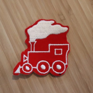 May include: Red embroidered iron-on patch of a train with white details. The train has a white smoke plume, a white chimney, and white wheels.
