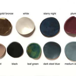 Puede incluir: Una colecci&oacute;n de peque&ntilde;os cuencos de cer&aacute;mica de forma irregular en varios colores. Los colores incluyen aztec gold/bronce, blanco, starry night, ciruela, camel, negro, verde hoja, azul acero oscuro y azul acero medio. Cada cuenco tiene una forma org&aacute;nica.