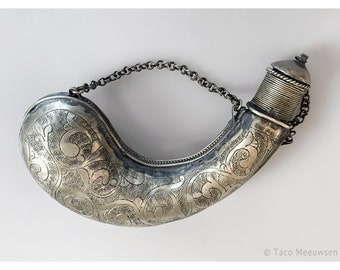 May include: A silver flask with an ornate floral design and a chain handle. The flask has a hinged lid and is decorated with a repeating pattern of leaves and flowers.