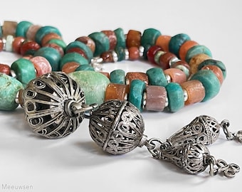 May include: A multi-strand necklace with turquoise, pink, and orange beads. The necklace has two silver filigree pendant charms.