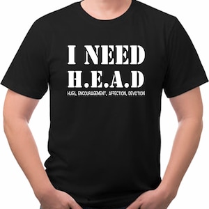 May include: Black t-shirt with white text that reads "I NEED H.E.A.D." with the words "HUGS, ENCOURAGEMENT, AFFECTION, DEVOTION" below. The shirt is a crew neck style.