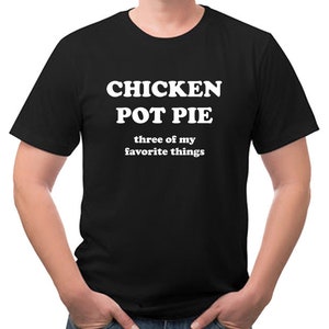 May include: Black t-shirt with the words "CHICKEN POT PIE" in large white letters, followed by "three of my favorite things" in smaller white text. The shirt is being worn.