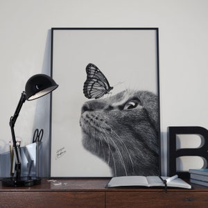 Disegno a carboncino iperrealistico di un gattino e di una farfalla delicatamente posata sul suo naso, stampato su carta satinata bianca di alta qualità