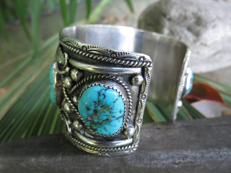 May include: Silver cuff bracelet with turquoise stones and intricate silver designs.