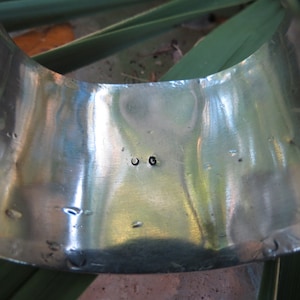 May include: Close-up of the inside of a silver bracelet with the letters "OG" stamped on the metal.