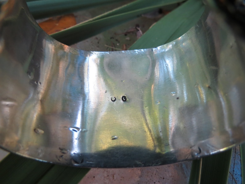 May include: Close-up of the inside of a silver bracelet with the letters "OG" stamped on the metal.