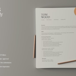 Op de afbeelding: Een cv-sjabloon met de naam "Tom Wood" bovenaan. Het cv staat op een wit vel papier met een lichtgrijze achtergrond. De woorden "ATS ready" staan linksboven. Een potlood ligt rechts.
