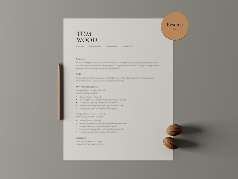 Op de afbeelding: Een cv-sjabloon met de naam "TOM WOOD" bovenaan. Het document bevat secties voor samenvatting, vaardigheden, professionele ervaring en opleiding. Een houten potlood en twee decoratieve noten zijn bij het document geplaatst. Een ronde sticker met het woord "Resume" staat rechtsboven.