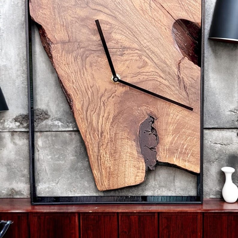 May include: A wooden clock with black hands and a black frame. The clock face is a natural wood slice with a unique grain pattern.