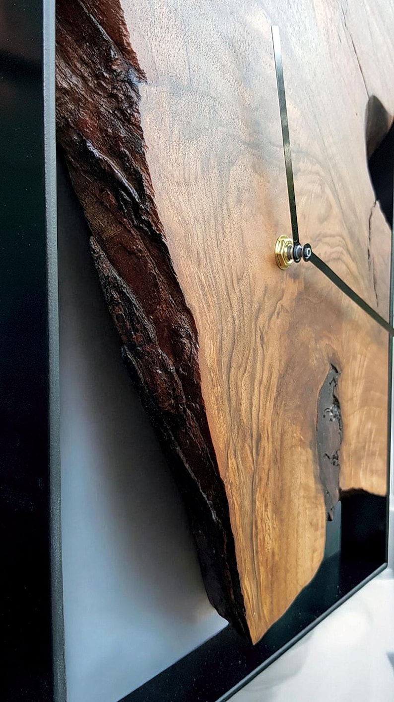 May include: A wooden clock with a black frame and black hands. The clock face is a natural wood slice with a unique grain pattern.