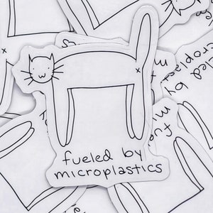 Peut inclure: Un dessin au trait noir et blanc d'un chat avec le texte "fueled by microplastics" en dessous.