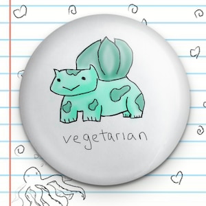Peut inclure: Un bouton blanc avec un dessin animé d'un Bulbasaur Pokemon vert avec le texte "végétarien" en dessous.