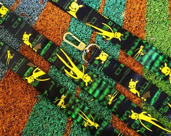 May include: Four black and green lanyards with a yellow cartoon character design. The lanyards have a metal clip and a loop at the end.