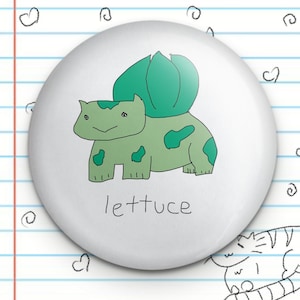 Peut inclure: Un bouton blanc avec un personnage de dessin animé vert avec un dos vert feuillu et le mot "lettuce" écrit en dessous.