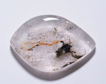 Puede incluir: Un cabujón de cuarzo transparente con inclusiones dendríticas en tonos de negro, marrón y naranja. Las inclusiones se asemejan a ramas o helechos.