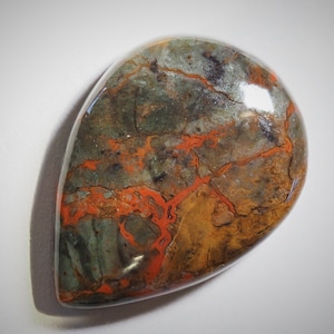 May include: A teardrop-shaped cabochon of green, brown, and orange jasper with a polished surface.