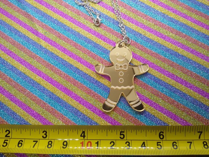 May include: Gold-colored gingerbread man pendant necklace. The pendant is about 4 inches tall and is on a silver chain.