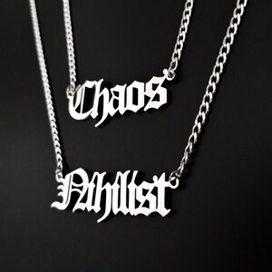 May include: Two silver-colored necklaces with chain links. The top necklace spells "Chaos" in a gothic font. The bottom necklace spells "Ahlilst" in a gothic font. The background is black.