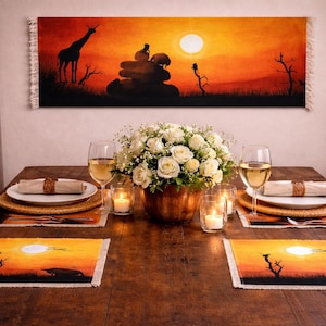 May include: A dining table set for a special occasion. The table is set with white plates, wine glasses, and candles. A large floral arrangement sits in the center. Above the table is a decorative tapestry with a sunset scene.