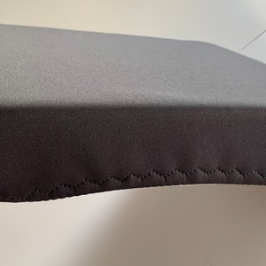 May include: A gray fabric seat cushion with a zig-zag stitch around the edge.