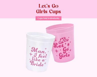 May include: Two plastic stadium cups, one white and one light pink, featuring pink text and star graphics. The white cup reads Man, I feel like a Bride, and the pink cup features a cowboy hat graphic with the text Let's Go Girls.