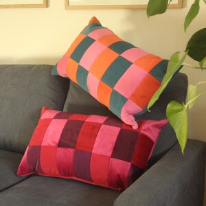 May include: Two rectangular cushions with a chequered pattern in pink, orange, teal, red and burgundy. The cushions are on a grey sofa. Home decor item. The cushions are approximately 40cm x 60cm.