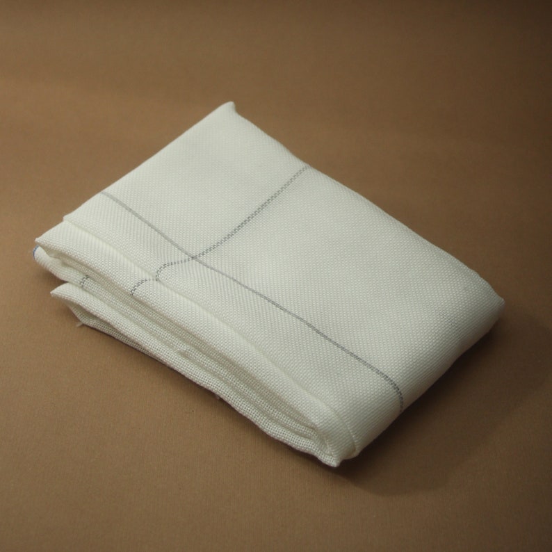 May include: Folded white cloth napkin with a subtle grid pattern in light gray. The napkin is made of a textured fabric and is neatly folded, suggesting a formal setting or elegant dining.