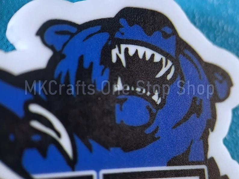 May include: A blue and black bear with a fierce expression, its mouth open and teeth bared. The bear is on a white background.