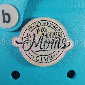 K&ouml;nnte beinhalten: Ein wei&szlig;er und rosafarbener Glitzer-Anh&auml;nger mit dem Text "Proud Member of the Hot Mess Moms Club" in schwarzen Buchstaben.