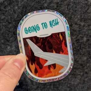 Może przedstawiać: Holograficzna naklejka z srebrną obwódką i wzorem płomieni w kolorze czerwonym, pomarańczowym i żółtym. Naklejka przedstawia białe skrzydło samolotu z napisem "GOING TO HELL" w kolorze turkusowym.