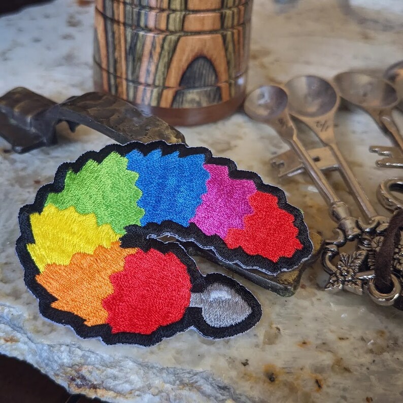 Puede incluir: Parche bordado arco&iacute;ris con forma de cola y una cuchara de plata en el extremo.