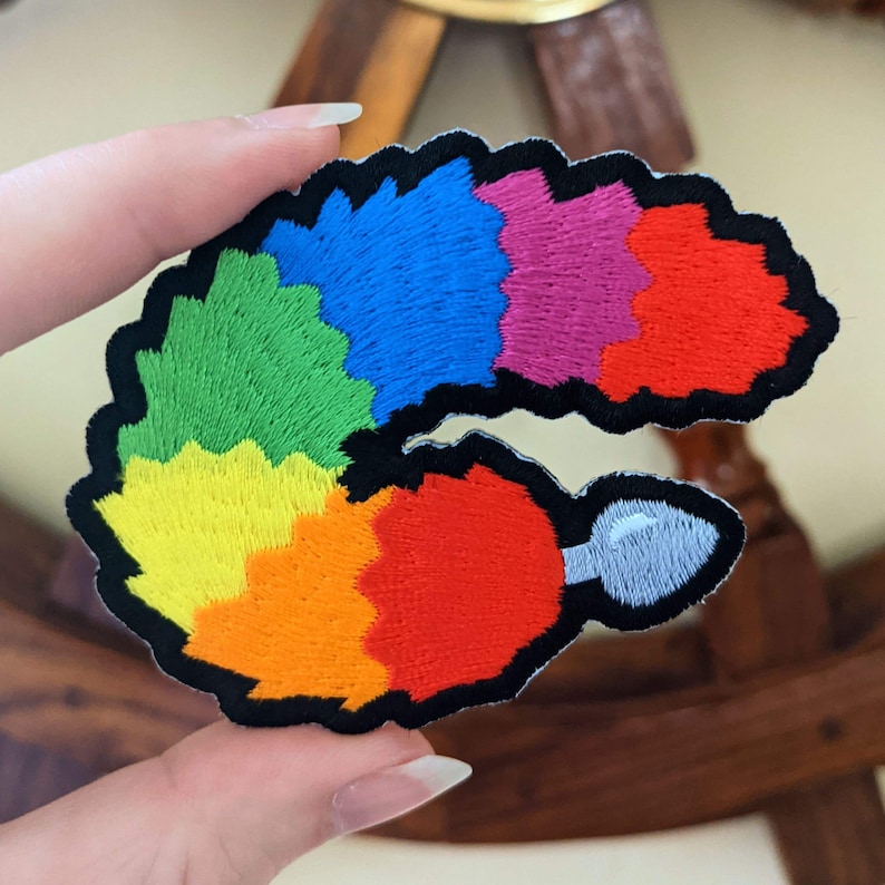 Puede incluir: Parche bordado en forma de cola curvada con una peque&ntilde;a punta blanca, en colores arco&iacute;ris.