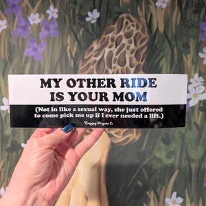 May include: A white bumper sticker with black and blue text that reads "MY OTHER RIDE IS YOUR MOM." Below the main text is a smaller line of text that says "(Not in like a sexual way, she just offered to come pick me up if I ever needed a lift.)".