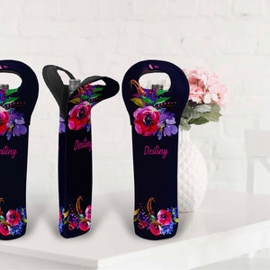 May include: Navy blue wine bottle sleeve with a floral design featuring red and purple flowers. The word "Destiny" is written in pink script. The sleeve has a handle for easy carrying and is designed to hold a standard wine bottle.