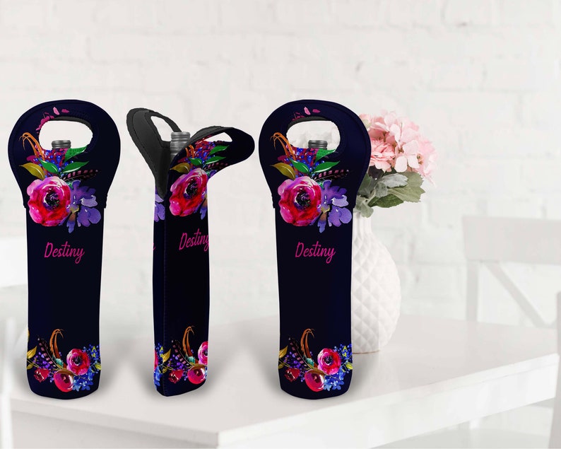 May include: Navy blue wine bottle sleeve with a floral design featuring red and purple flowers. The word "Destiny" is written in pink script. The sleeve has a handle for easy carrying and is designed to hold a standard wine bottle.