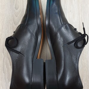 May include: A pair of black leather lace-up shoes with a rounded toe and a low heel.