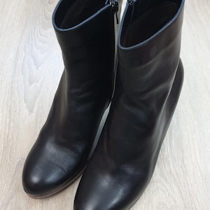Puede incluir: Un par de botines de cuero negro con cremallera lateral.
