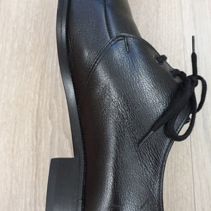 May include: A pair of black leather lace-up shoes with a rounded toe and a thick sole.