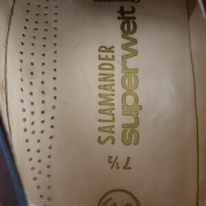 May include: Close-up of the inside of a brown leather shoe. The insole is beige with the text "Superweit" and "Salamander" printed in gold. The size is marked as "7 1/2".