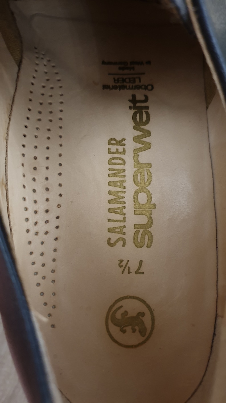 May include: Close-up of the inside of a brown leather shoe. The insole is beige with the text "Superweit" and "Salamander" printed in gold. The size is marked as "7 1/2".