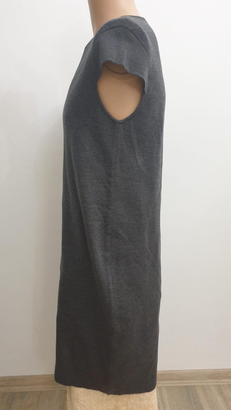 Puede incluir: Un vestido gris oscuro de manga corta. El vestido tiene una silueta simple y recta y un cuello redondo. La tela parece ser un material de punto suave. El vestido se exhibe en un maniqu&iacute;.