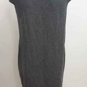 Puede incluir: Un vestido gris oscuro con mangas cortas y un detalle de espalda con abertura de cerradura. El vestido tiene un dise&ntilde;o simple y aerodin&aacute;mico, y est&aacute; hecho de una tela suave, posiblemente de punto. Dos peque&ntilde;os botones aseguran la abertura de la cerradura en la espalda.