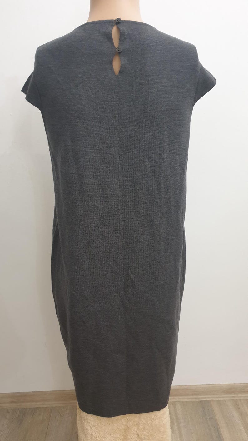 Puede incluir: Un vestido gris oscuro con mangas cortas y un detalle de espalda con abertura de cerradura. El vestido tiene un dise&ntilde;o simple y aerodin&aacute;mico, y est&aacute; hecho de una tela suave, posiblemente de punto. Dos peque&ntilde;os botones aseguran la abertura de la cerradura en la espalda.